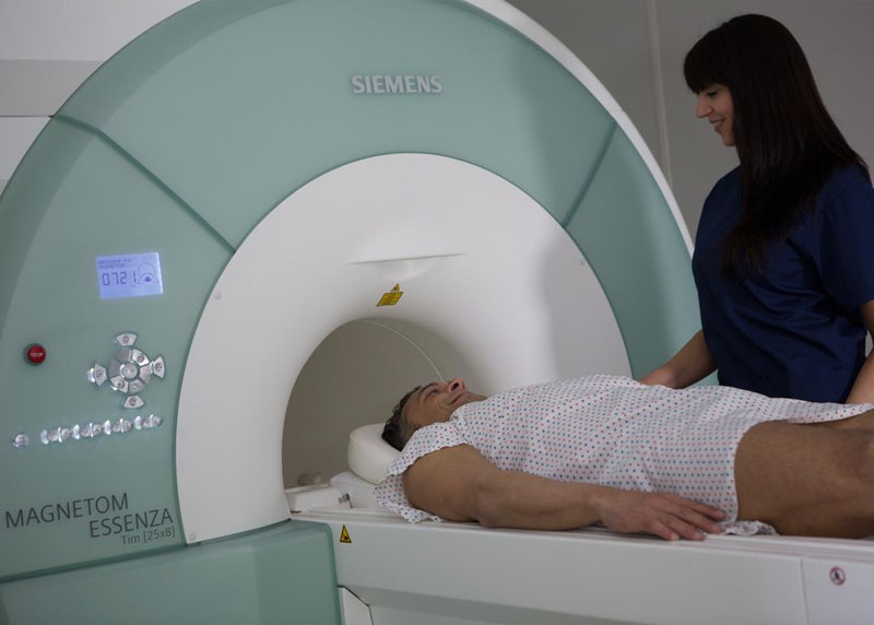 Patient in MRI scanner next to a radiologist